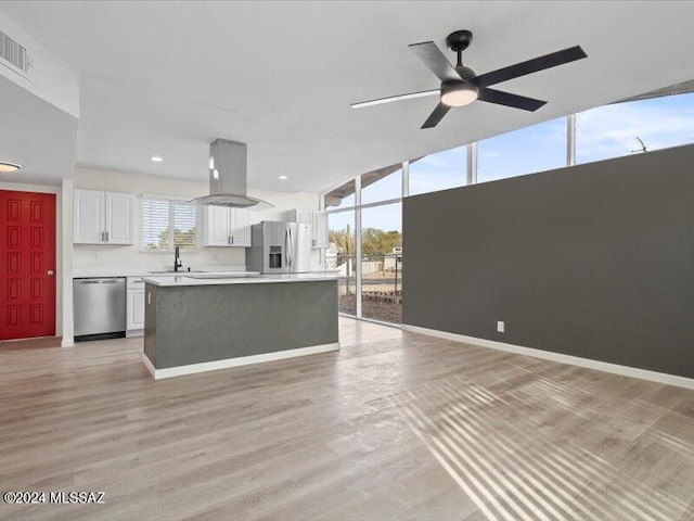 kitchen featuring appliances with stainless steel finishes, a center island, light hardwood / wood-style floors, white cabinetry, and range hood