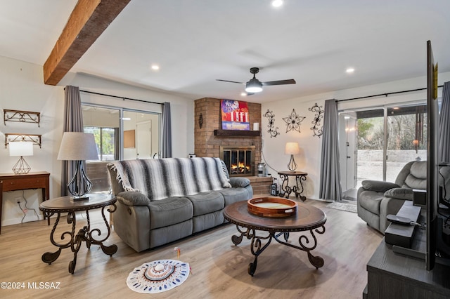 living room with hardwood / wood-style floors, plenty of natural light, beamed ceiling, and a brick fireplace