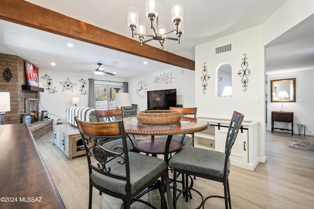 dining area featuring a fireplace, ceiling fan with notable chandelier, light hardwood / wood-style floors, and beamed ceiling