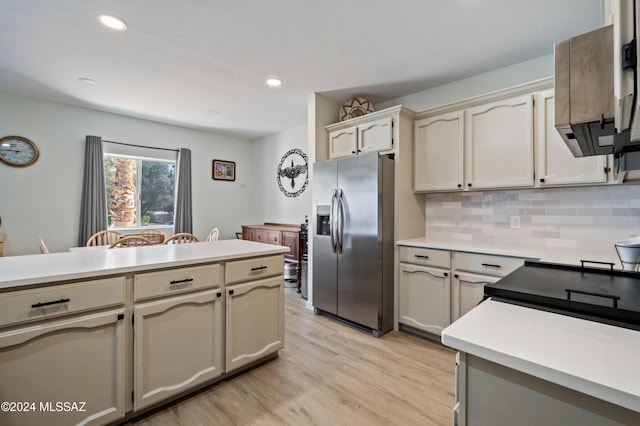 kitchen with stainless steel refrigerator with ice dispenser, light wood-type flooring, cream cabinets, and backsplash