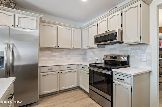 kitchen featuring appliances with stainless steel finishes, backsplash, and light hardwood / wood-style floors