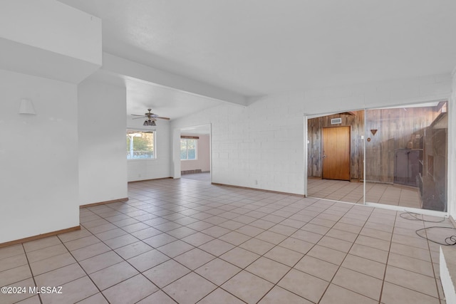 empty room with light tile patterned floors, vaulted ceiling with beams, and ceiling fan