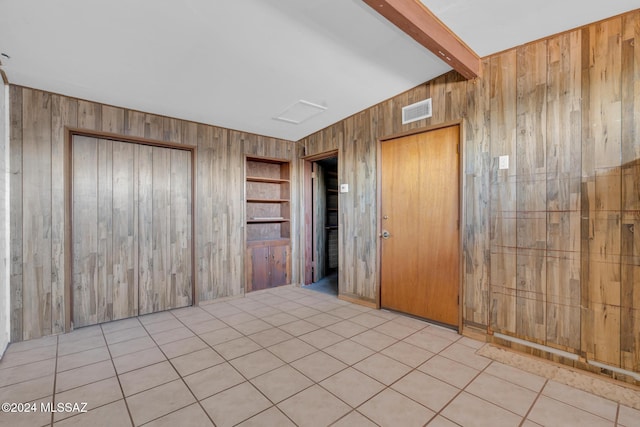 spare room with wood walls, light tile patterned floors, and beam ceiling