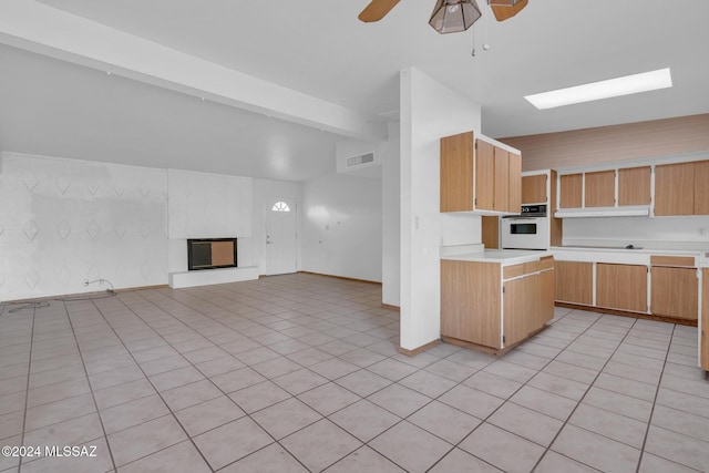 kitchen featuring ceiling fan, white oven, vaulted ceiling with beams, a multi sided fireplace, and light tile patterned flooring