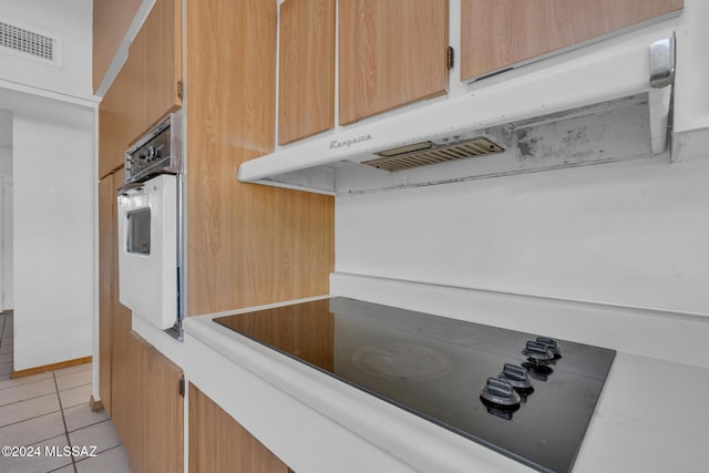 kitchen featuring white oven, black electric stovetop, and light tile patterned floors