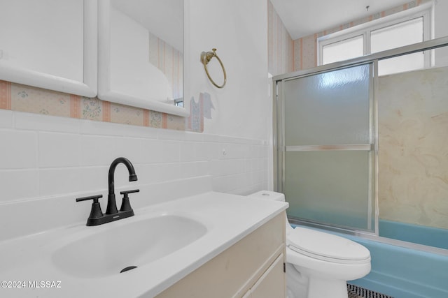 full bathroom featuring vanity, toilet, and shower / bath combination with glass door