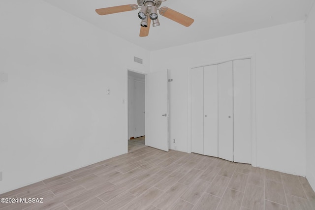 unfurnished bedroom featuring ceiling fan, a closet, and light hardwood / wood-style flooring