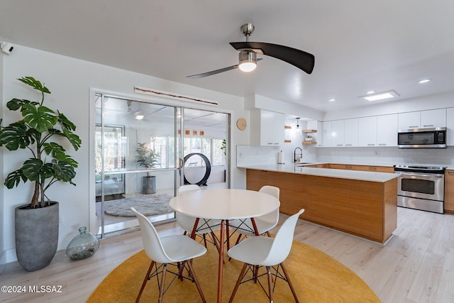 dining room featuring ceiling fan, sink, and light hardwood / wood-style floors