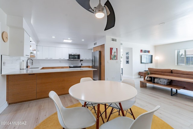 dining area with light hardwood / wood-style flooring, ceiling fan, and sink