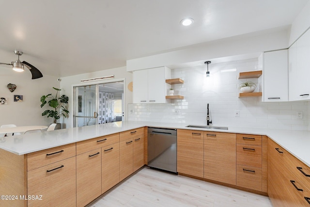 kitchen with stainless steel dishwasher, sink, white cabinetry, and kitchen peninsula