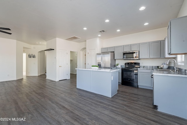 kitchen with a center island, sink, dark hardwood / wood-style floors, gray cabinets, and appliances with stainless steel finishes