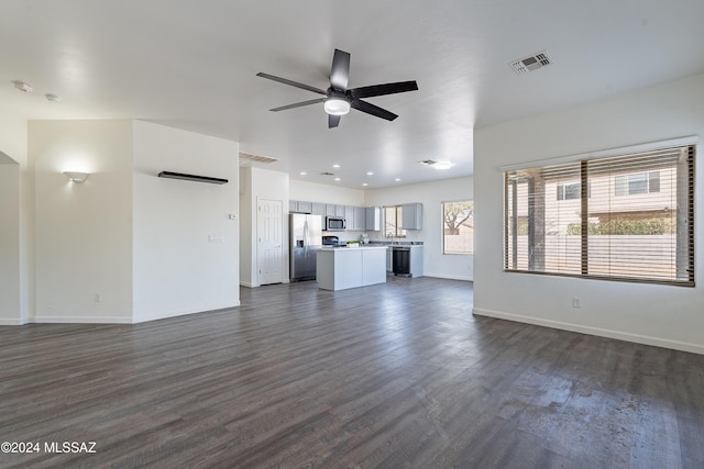 unfurnished living room with a wealth of natural light, ceiling fan, and dark wood-type flooring