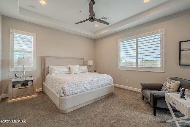 bedroom featuring a raised ceiling, multiple windows, ceiling fan, and carpet