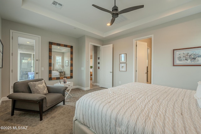 carpeted bedroom with ceiling fan and a tray ceiling