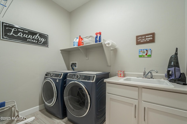 laundry room featuring sink, cabinets, light wood-type flooring, and independent washer and dryer