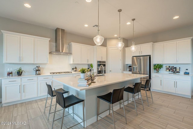 kitchen with pendant lighting, white cabinets, a center island with sink, wall chimney exhaust hood, and decorative backsplash