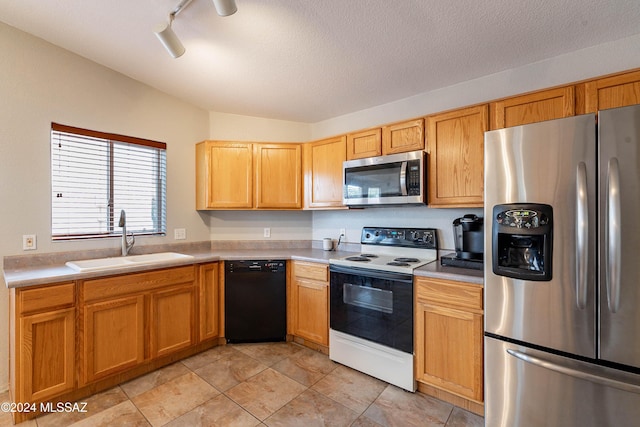 kitchen featuring appliances with stainless steel finishes, track lighting, a textured ceiling, vaulted ceiling, and sink