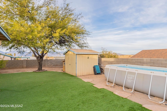 view of yard with a fenced in pool and a storage shed