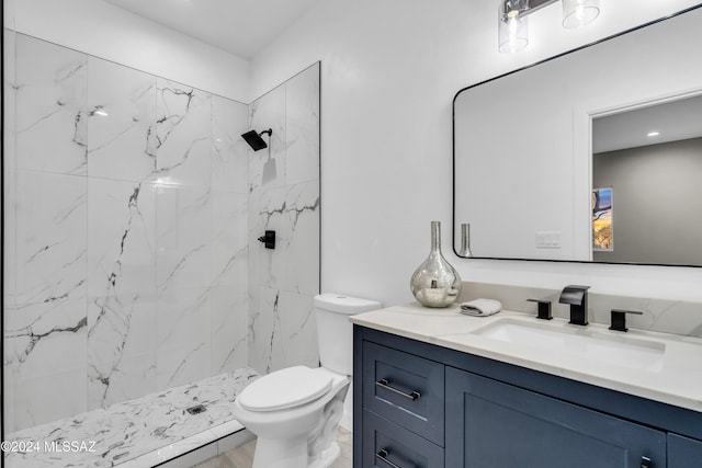 bathroom with a tile shower, vanity, and toilet