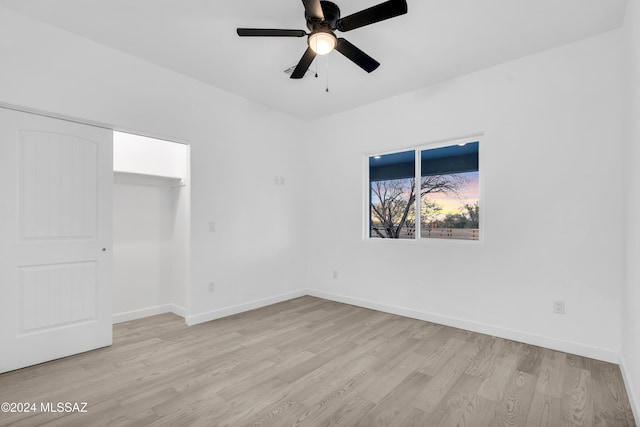 unfurnished bedroom featuring ceiling fan, a closet, and light hardwood / wood-style flooring