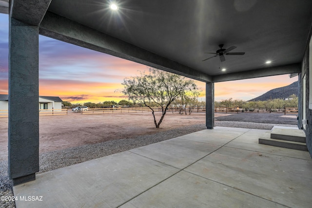 patio terrace at dusk featuring a mountain view and ceiling fan