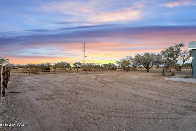 yard at dusk featuring a rural view