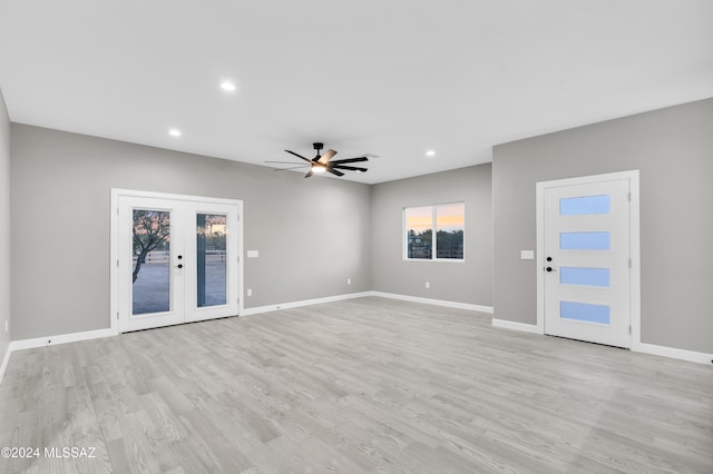 unfurnished living room featuring ceiling fan, french doors, and light wood-type flooring