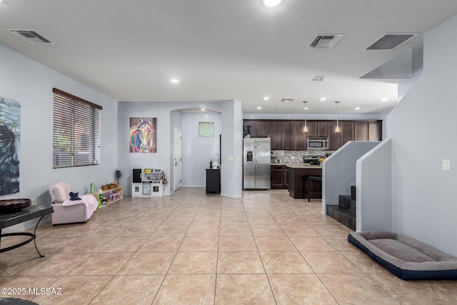 kitchen with dark brown cabinetry, light tile patterned floors, tasteful backsplash, a kitchen island, and appliances with stainless steel finishes