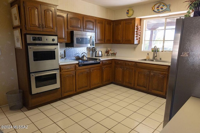 kitchen with a sink, stainless steel appliances, decorative backsplash, and light countertops
