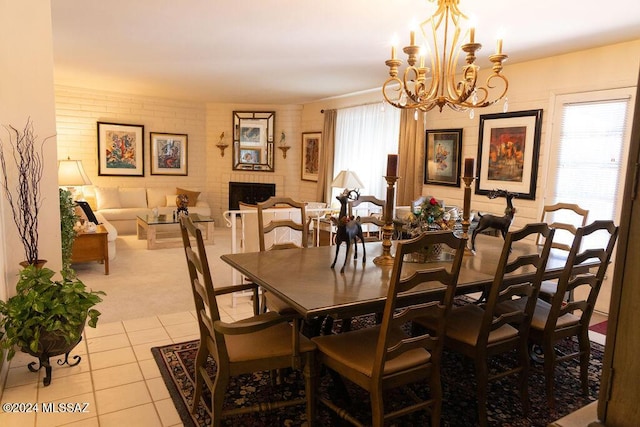 tiled dining area featuring a chandelier and a brick fireplace