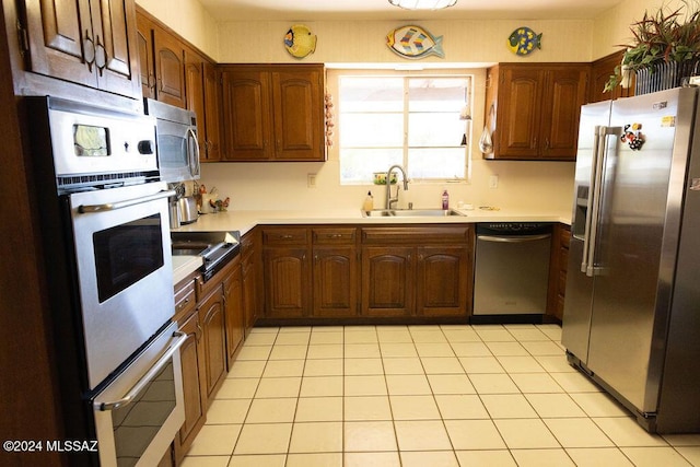 kitchen with light countertops, light tile patterned flooring, stainless steel appliances, a warming drawer, and a sink