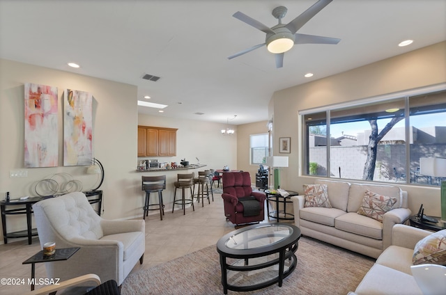 tiled living room with ceiling fan with notable chandelier