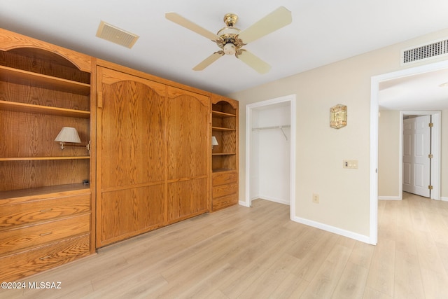 unfurnished bedroom with a closet, light hardwood / wood-style floors, a spacious closet, and ceiling fan