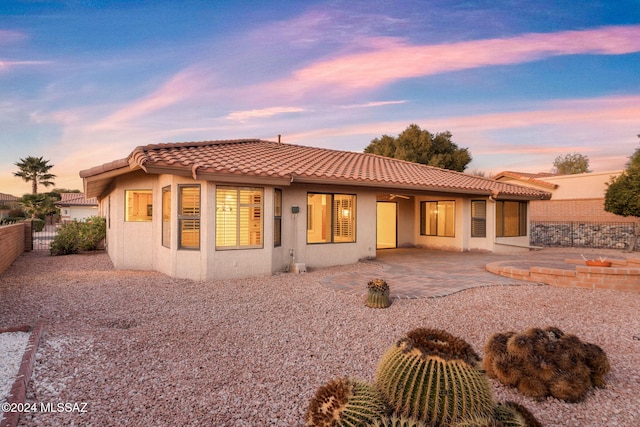 back house at dusk featuring a patio and an outdoor fire pit