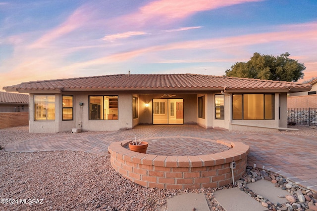 back house at dusk featuring a patio area