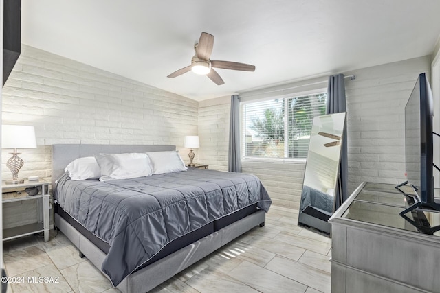 bedroom with ceiling fan and brick wall