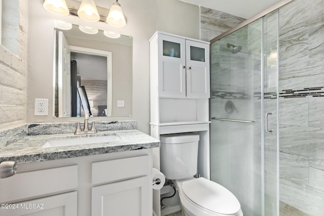 bathroom with vanity, toilet, a shower with shower door, and a notable chandelier