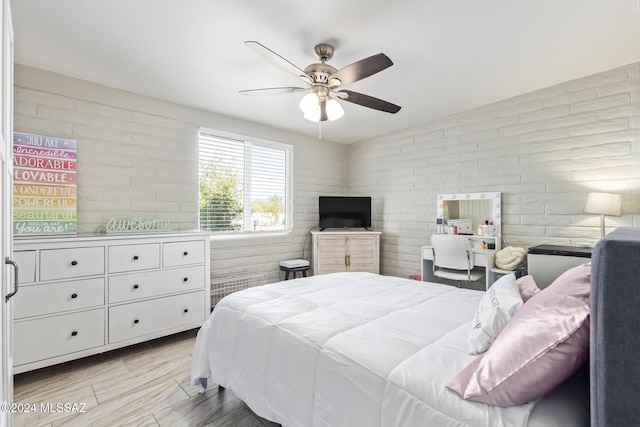 bedroom featuring ceiling fan and brick wall