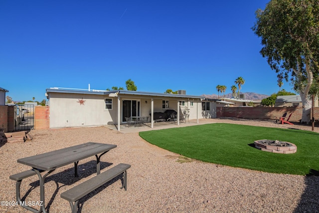 rear view of house with a fire pit, a yard, and a patio