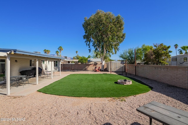 view of yard featuring a patio, a shed, and a fire pit