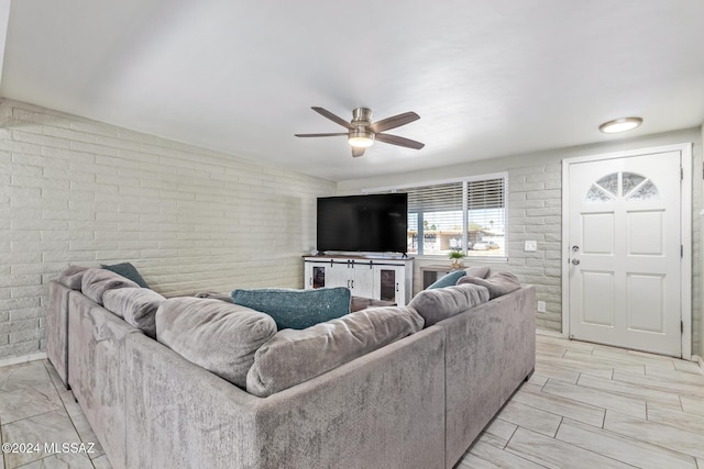 living room featuring ceiling fan and brick wall