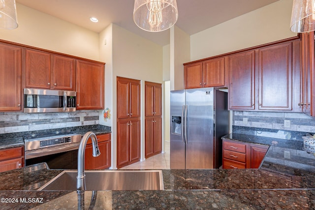 kitchen featuring sink, hanging light fixtures, dark stone countertops, appliances with stainless steel finishes, and tasteful backsplash