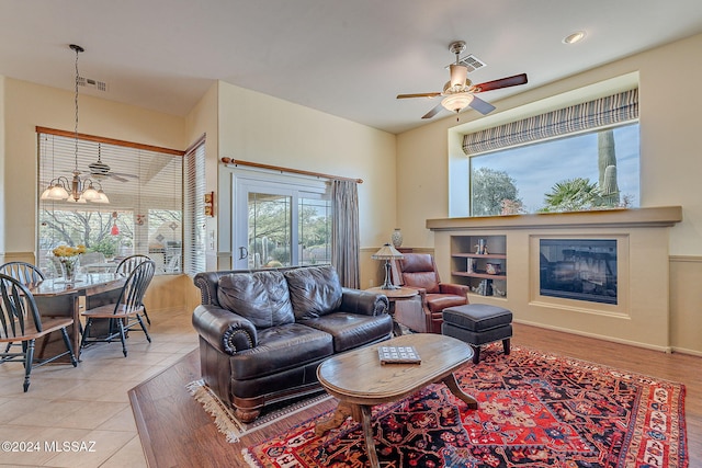 living room featuring ceiling fan with notable chandelier and light tile patterned flooring