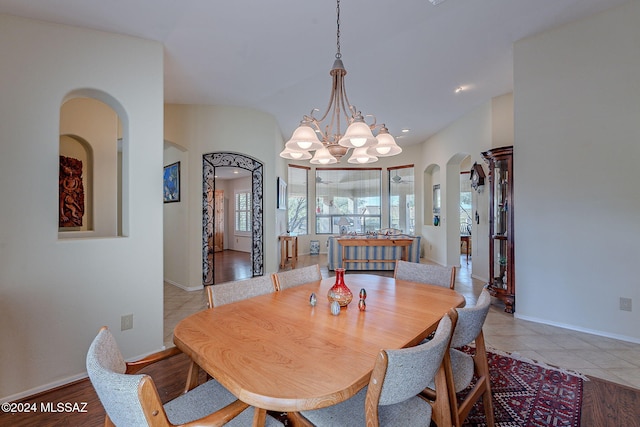 dining area with light tile patterned floors, a chandelier, and vaulted ceiling