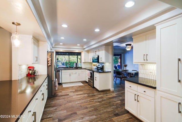 kitchen featuring white cabinets, stainless steel appliances, hanging light fixtures, and dark wood-type flooring