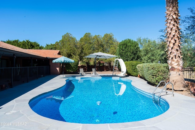 view of swimming pool with a patio and a water slide