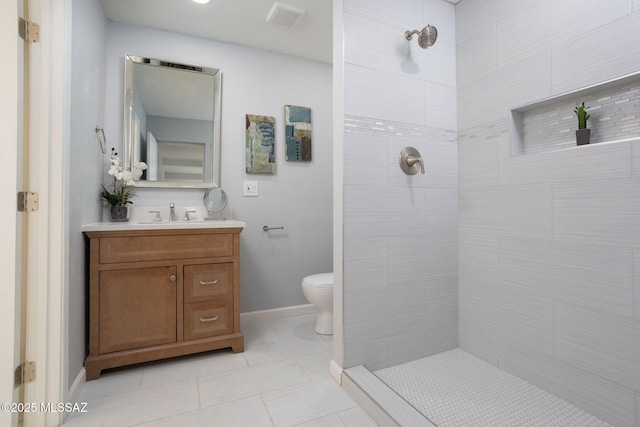 bathroom featuring vanity, tile patterned floors, toilet, and tiled shower