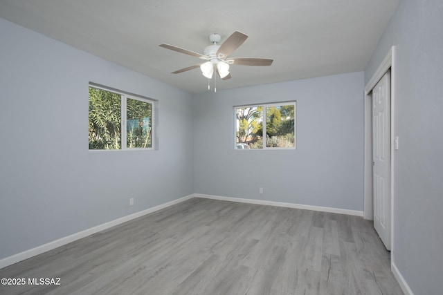 empty room with ceiling fan, a healthy amount of sunlight, and light hardwood / wood-style floors