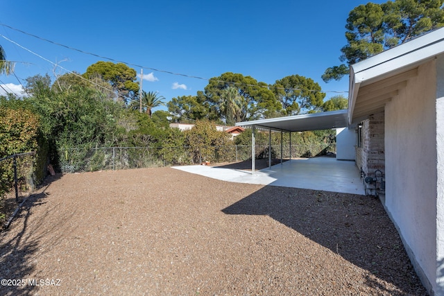 view of yard with driveway, a fenced backyard, and an attached carport