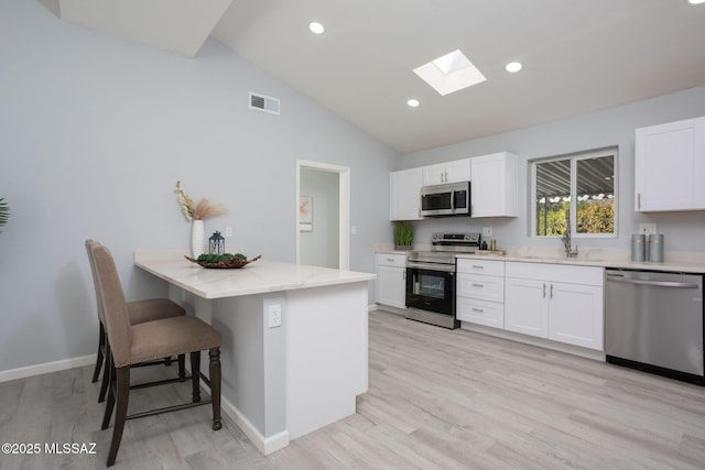 kitchen featuring stainless steel appliances, a breakfast bar, and white cabinets